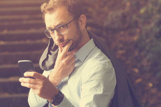 年轻英俊的男子使用智能手机。图片下载