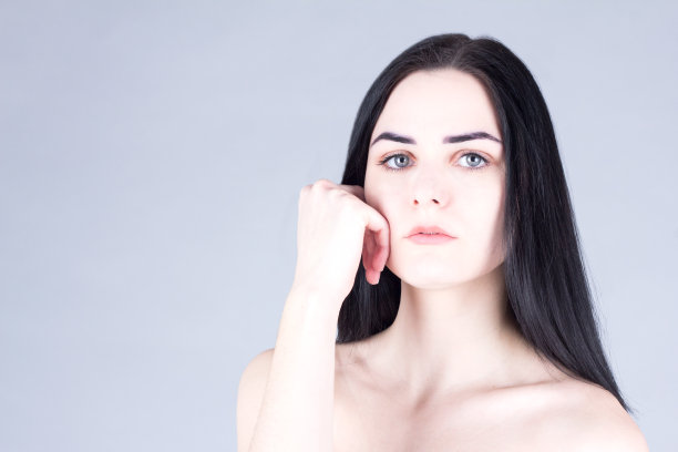 黑发女人摸着她的脸颊，看着镜头图片下载