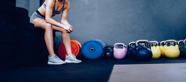 女孩休息后坐在健身房的重量上的细节图片下载