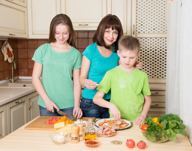 快乐的家庭在厨房做披萨。图片下载