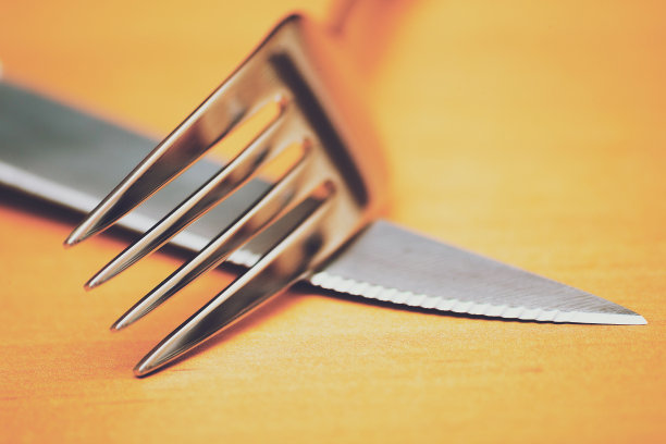 一个银色的刀叉在一个棕色的桌子上的特写图片下载