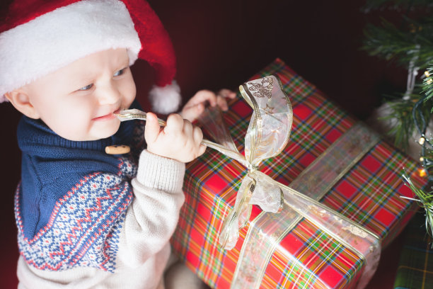 圣诞假期。婴儿在圣诞老人的帽子打开礼物盒图片下载