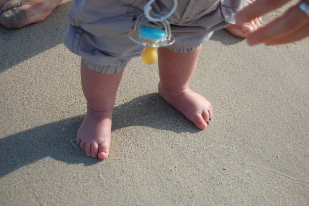 婴儿的脚在沙滩上的沙子里图片下载