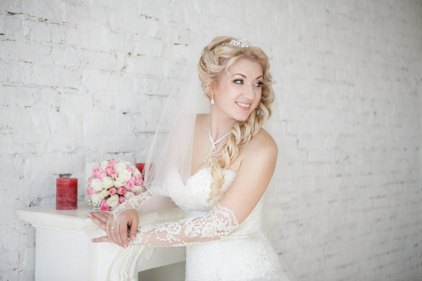 漂亮的新娘拿着婚礼花束站在壁炉旁边图片下载