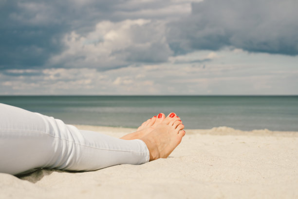 女性脚与红色足疗在海滩上图片下载