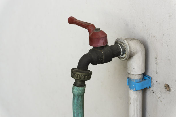 白色墙壁上的旧水龙头和水管。图片下载