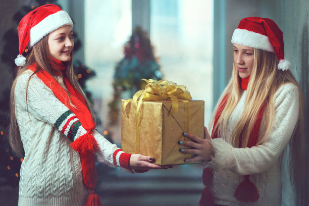 两个女孩在圣诞树前拿着礼物图片下载