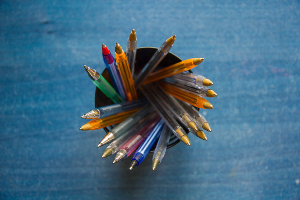 桌子上一个箱子里装着不同颜色的笔。图片下载