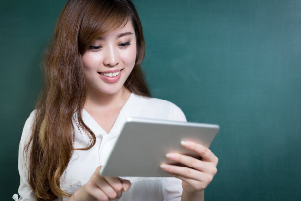 亚洲美女拿着写字板在黑板前图片下载