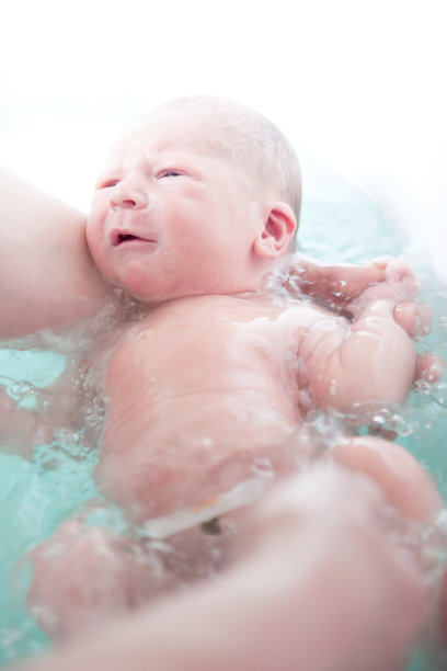 漂亮的新生男婴在蓝色的浴缸里洗澡图片下载