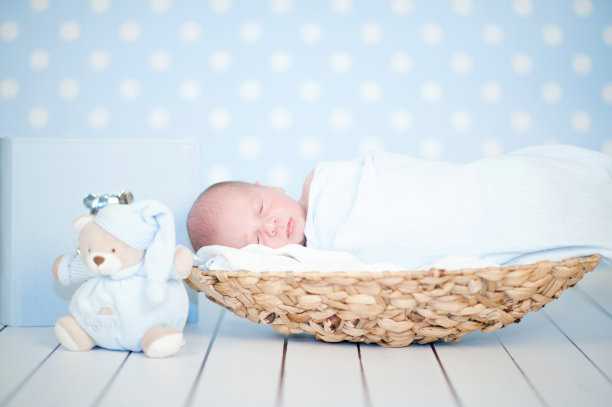 一张新生儿蜷缩在篮子里睡觉的照片图片下载