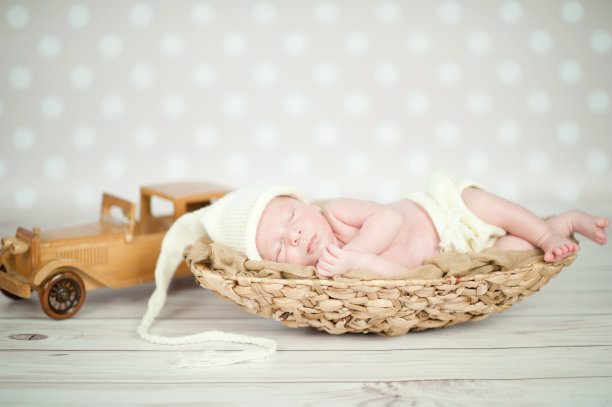 一张新生儿蜷缩在篮子里睡觉的照片图片下载