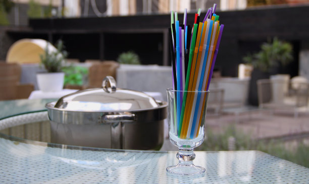 酒吧桌上的透明玻璃杯中的彩色鸡尾酒吸管图片下载