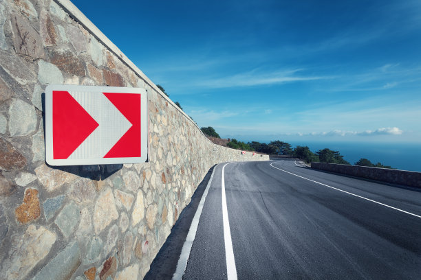 柏油路在秋日的森林里和日出的路标图片下载