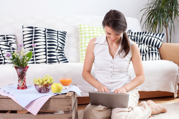 年轻女子，坐在地板上通过电脑阅读图片下载