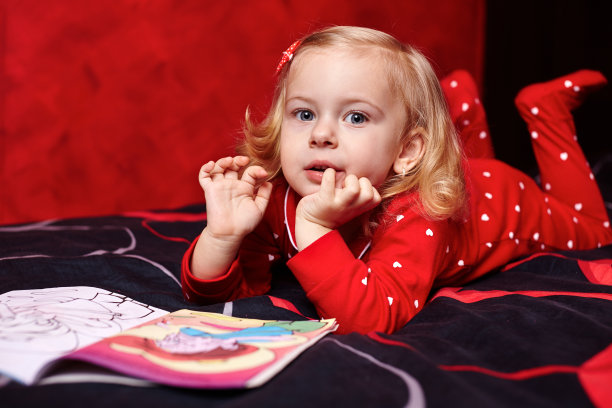 可爱的女孩在床上看书图片下载