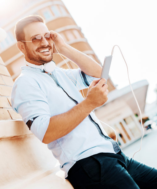 英俊的年轻微笑的男子与平板电脑的肖像。听图片下载