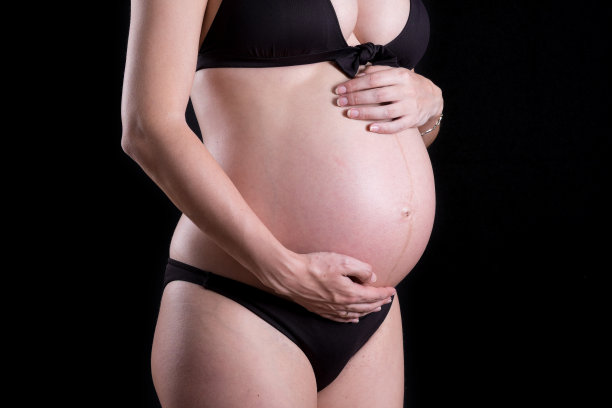 一个可爱的怀孕的腹部与黑色背景的特写图片下载