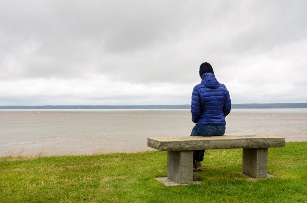 一个阴天独自坐在长椅上的女人图片下载