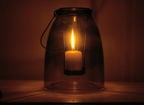 一个在玻璃杯里燃烧的蜡烛的特写镜头图片下载