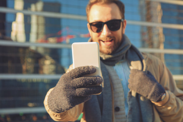 戴着手套用手机的现代人。图片下载