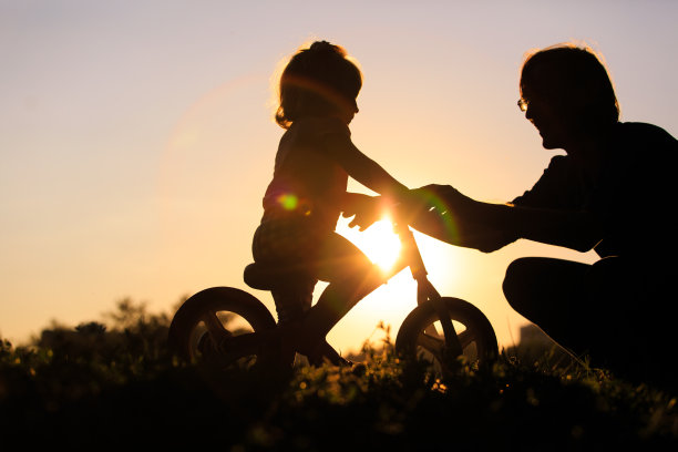父亲教女儿在日落时分骑自行车图片下载