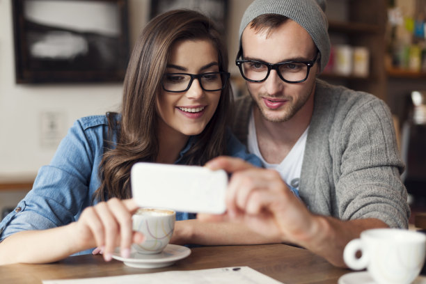 时髦情侣在咖啡馆用手机图片下载