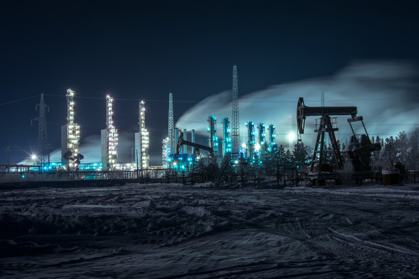 石油钻塔和明亮的工业现场在晚上。素材图片
