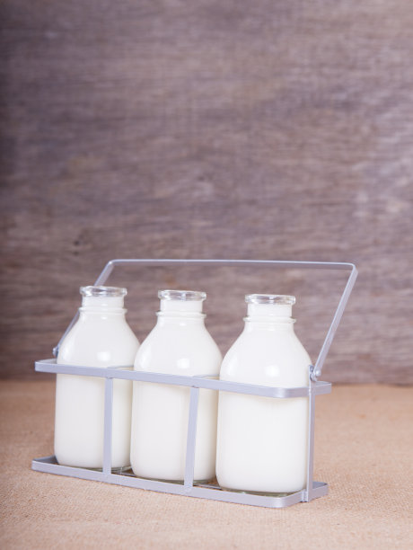 桌子上放着三个装满牛奶的瓶子图片下载