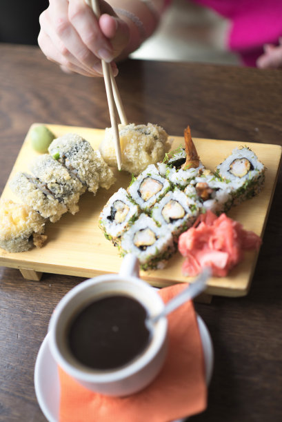 照片中的女性手拿筷子吃寿司图片下载