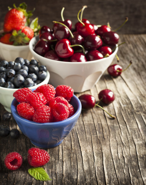 木背景上的碗里的新鲜浆果。图片下载