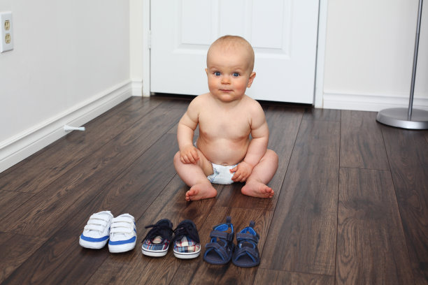 婴儿坐在他鞋子旁边的地板上图片下载