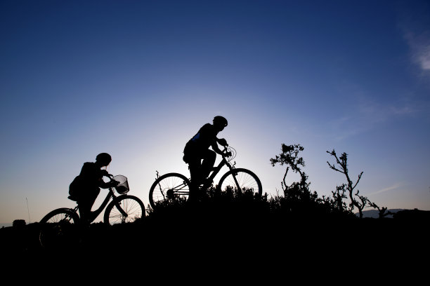 日落时分，年轻人和女孩骑着山地车图片下载