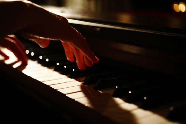 手在昏暗的光线下弹奏钢琴图片下载