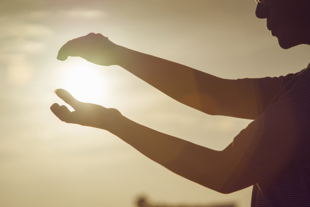 女人在日落的时候用两只手握住太阳图片下载