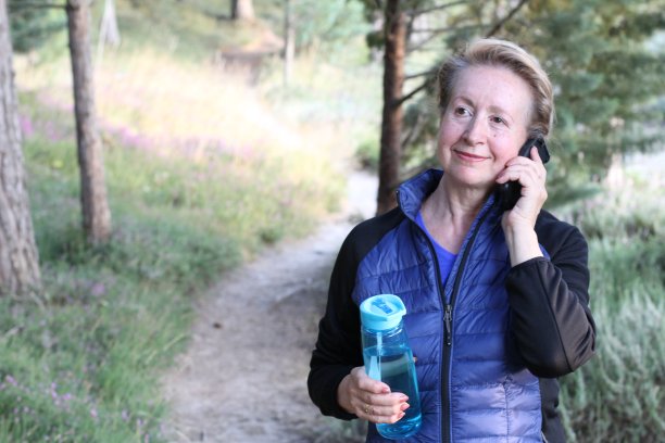 一位女士在森林里使用手机图片下载