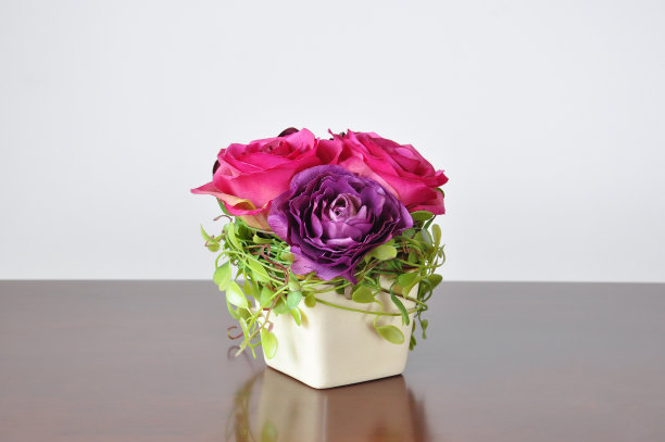 木桌上放着花瓶和人造花。图片下载