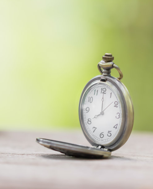 古董怀表在木桌上与模糊的自然背景图片下载