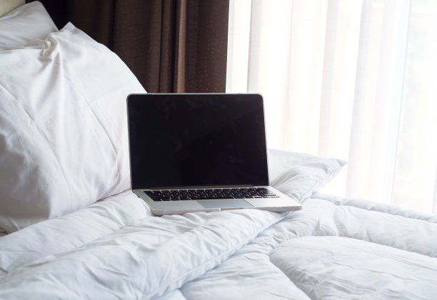 笔记本电脑在早上的白色床上。图片下载