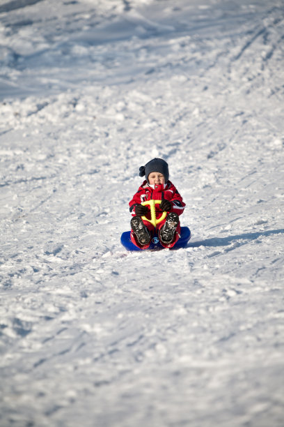 穿红衣服的男孩在雪橇上图片下载