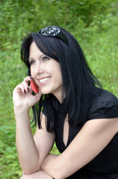 一个穿着黑色裙子拿着手机的微笑女孩图片下载