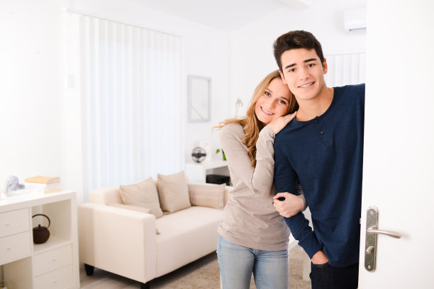 幸福的年轻夫妇打开门，欢迎朋友在公寓图片下载