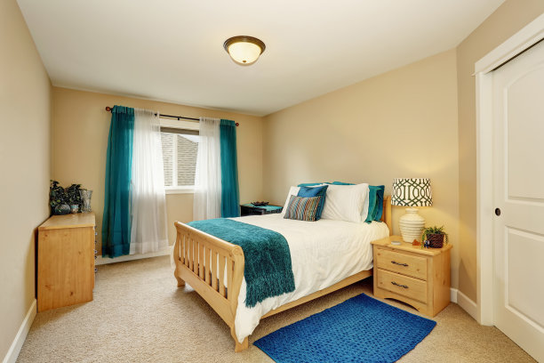 整洁的米色卧室，绿松石窗帘和木床图片下载