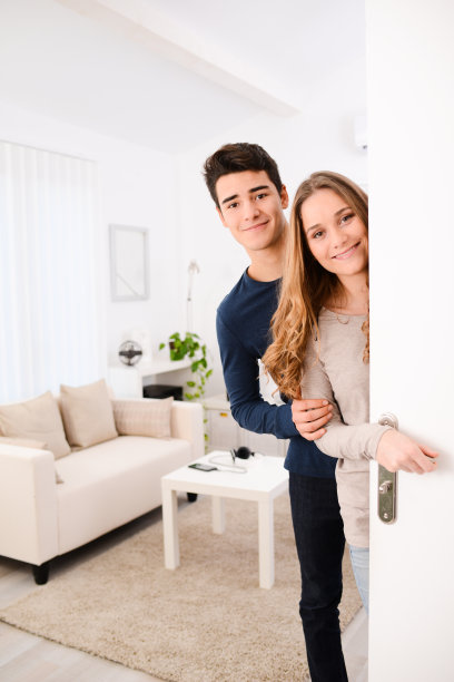 幸福的年轻夫妇打开门，欢迎朋友在公寓图片下载