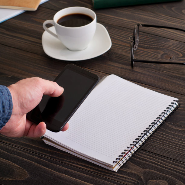 男人用智能手机工作为办公室的木桌图片下载