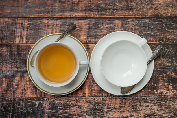 旧木桌上放着空茶杯和满茶杯图片下载