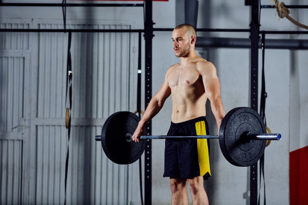 年轻运动员在体育馆举重时举杠铃图片下载