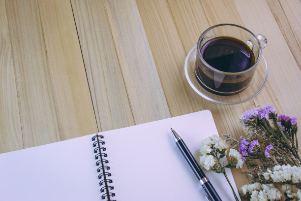 把笔放在空白笔记本上，放在热咖啡杯旁边图片下载