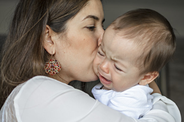 年轻的母亲在安抚哭闹的婴儿图片下载