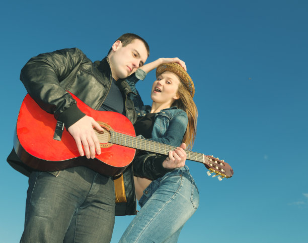 年轻漂亮的女人和年轻的男人在弹吉他图片下载